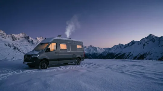 Camping-car en montagne enneigée lors d'une nuit froide d'hiver avec équipements hivernaux